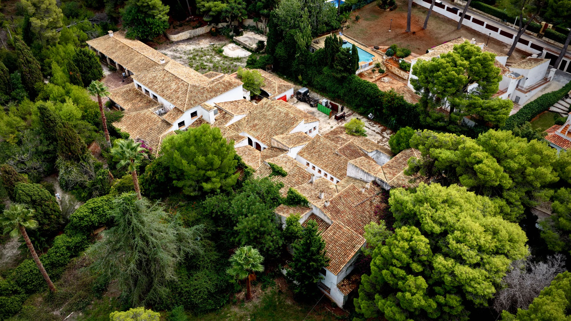 Casa Tosalet — aerial view of the whitewashed house and its tiled roofs among pines and palms